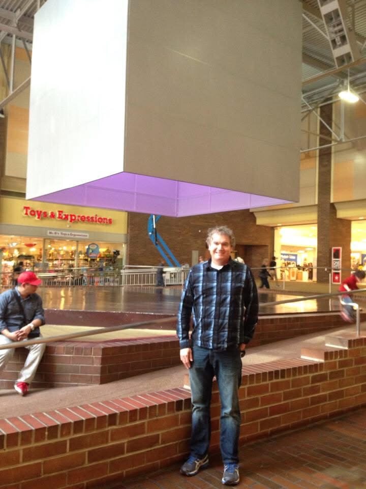 Russ Patterson standing under The Bloc cube
